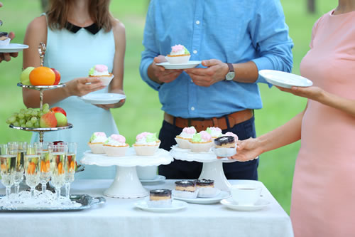 野外立食パーティーでカップケーキを手に取る人たち