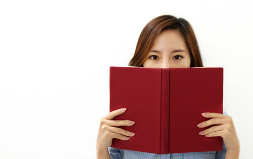 赤い本で顔を半分隠す女性